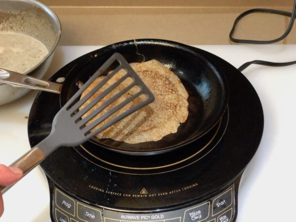 Flipping crepe over with spatula when crepe bottom is light brown color.