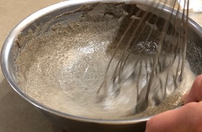 Whisking the water into buckwheat crepe batter until to get right consistency