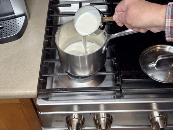 Pouring heavy cream into saucepan to make filling