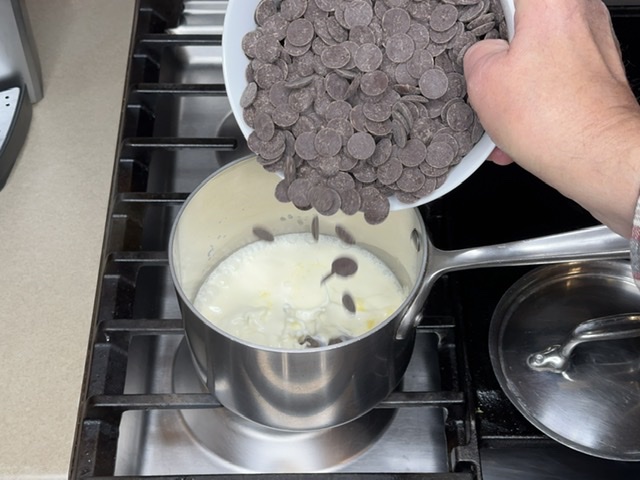 Adding 65% dark chocolate to hot cream.