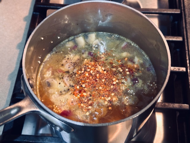 Chicken stock, chili pepper flakes, salt and pepper added to quinoa pilaf mixture