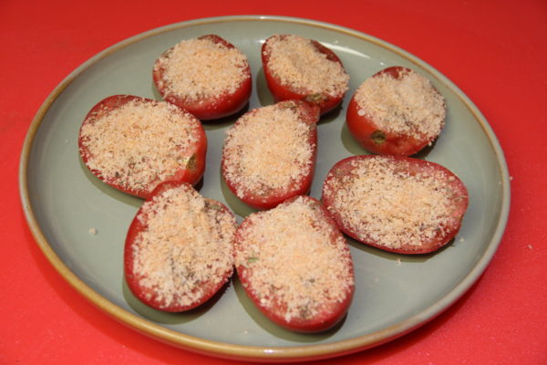 Tomato halves that's has a sprinkled Topping mixture over each one.