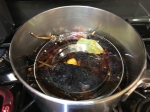 Cooking dried chilies, garlic weighted down with plate.