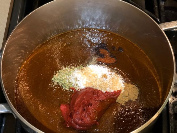 Adding all the aromatics to chili puree in sauce pan.