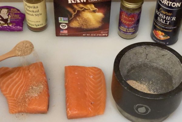 Sprinkling Spicy Seasoning Rub onto salmon filets.