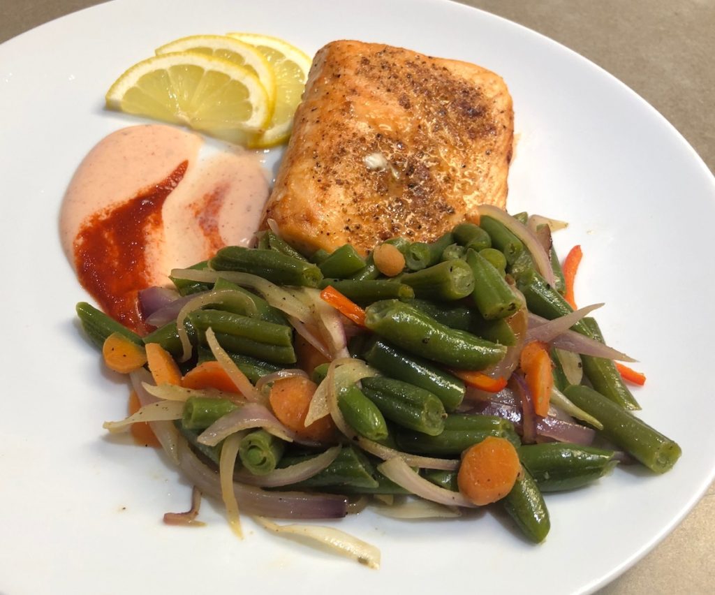 Garnished Spicy Air Fryer Salmon with sautéed green beans mix and Spicy Ranch Dressing