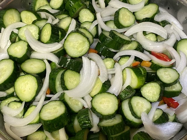 Iced down salted sliced cucumbers, onions, sweet peppers and cayenne pepper pieces.